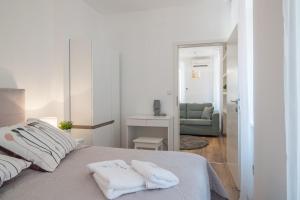 普拉Leona Deluxe Apartments的一间白色卧室,床上配有2条毛巾