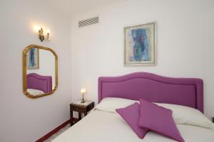 阿马尔菲卢斯公寓的一间卧室配有一张紫色的床和镜子