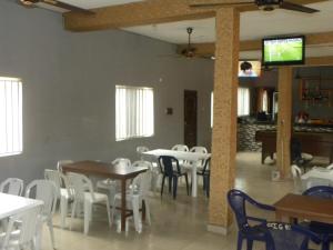 AlimoshoBiso Inn的一间带桌子和白色椅子的用餐室以及电视
