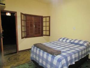 InhaúmaPousada Fazenda Bocaina的一间卧室配有一张带蓝白格子毯子的床