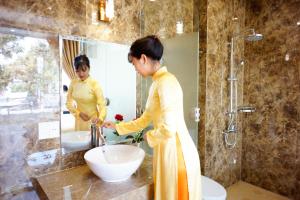 潘郎NỮ HOÀNG HOTEL的站在浴室水槽前的妇女