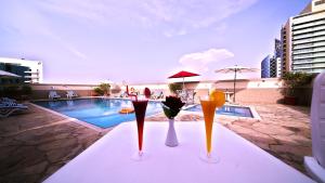 迪拜玫瑰花园公寓酒店 - 布尔迪拜的游泳池前桌上的三杯鸡尾酒