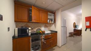 迪拜玫瑰花园公寓酒店 - 布尔迪拜的一间带木制橱柜和微波炉的厨房