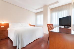 马德里Hotel Madrid Chamartín, Affiliated by Meliá的卧室配有白色的床和电视。