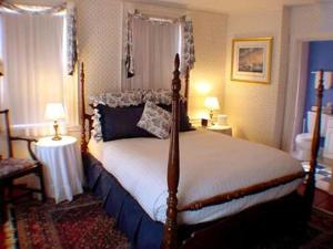 纽波特克拉克斯顿旅馆的一间卧室配有一张床、两张桌子和两盏灯。