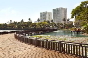 仰光Shangri-La Serviced Apartments, Yangon的公园里木板路,有水百合池塘