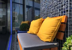 吕贝克吕贝克伽和瑞森藤维尔酒店的阳台上配有带两个黄色枕头的长凳