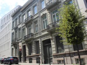 布鲁塞尔MAS Aparthotel EU的街道上的建筑物,前面有停车位