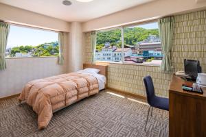 涩川市Stay View Ikaho的一间卧室配有一张床、一张书桌和两个窗户。