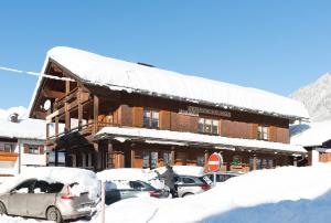 施科佩尔瑙穆斯布鲁格农场游公寓的一座有雪盖的建筑,前面有汽车停放