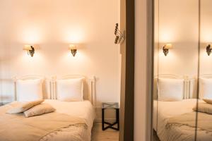 艾格-莫尔特Les suites du 17的一间卧室配有两张带白色枕头和镜子的床