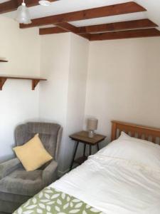 马汉莱斯Canol y Llan的一间卧室配有一张床、一把椅子和枕头