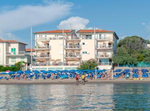 圣温琴佐Residence Villa Lo Scoglietto的一个带椅子和遮阳伞的海滩和一座建筑