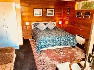 基督城Cosy studio apartment的卧室配有一张床铺,位于带木墙的房间内