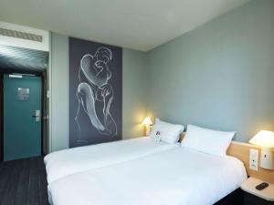 沙特尔宜必思沙特尔奥斯特卢斯酒店的卧室配有一张大床,墙上挂有绘画作品