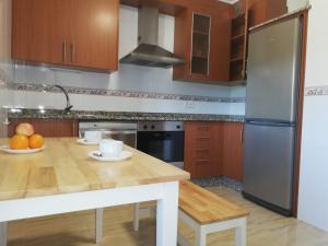 欧德鲁佐Pedrouzo Suites的厨房配有木桌和冰箱。