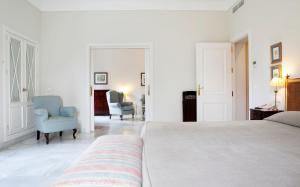 赫雷斯-德拉弗龙特拉赫雷斯别墅酒店的一间白色卧室,配有一张床和两把椅子