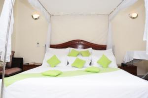 基加利Five to Five Hotel的卧室配有带绿色枕头的白色床