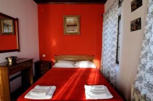 Psarádes腓力酒店 的红色卧室配有带2条毛巾的床