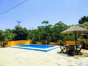 内尔哈Finca El Valle的一个带桌椅和遮阳伞的游泳池