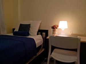 曼谷陈查拉99旅馆的一间卧室配有一张床和一张带台灯的桌子