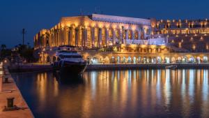 赫尔格达Pickalbatros Citadel Resort Sahl Hasheesh的夜间在水中划船的建筑物