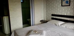 多明戈斯马丁斯Pousada na Montanha的卧室内的一张床位,卧室拥有白色砖墙