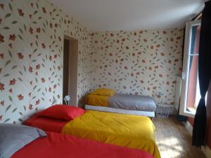 RevinGîte "La Maison"的一间设有三张床和色彩缤纷的毯子的房间