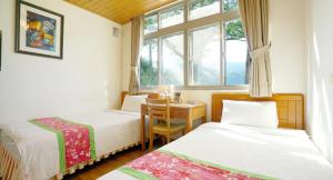 南庄乡红砖屋特色民宿的一间卧室设有两张床、一张桌子和一个窗口