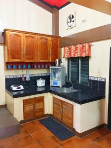 公主港Fully AC 3BR House for 8pax near Airport and SM with 100mbps Wifi的厨房配有木制橱柜和黑色台面