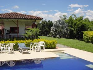 金巴亚Finca Hotel Santana Campestre的一个带白色椅子的游泳池以及一座房子