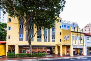 新加坡Fragrance Hotel - Balestier的一条有树的街道上的黄色建筑