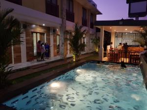 库塔Praba Guesthouse的夜间在房子前面的游泳池