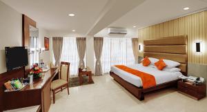 孟买Hotel Suba Galaxy Mumbai的酒店客房配有一张床、一张书桌和一台电视。