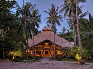 LikupangCoral Eye Boutique Resort and Marine Outpost的棕榈树海滩上的房子