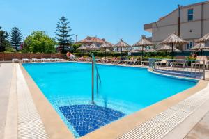 伊利索斯周日酒店的度假村的游泳池,配有椅子和遮阳伞