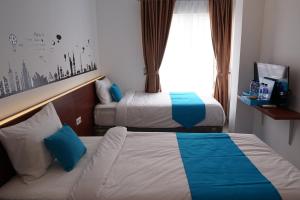 巨港Cemerlang Inn的酒店客房设有两张床和窗户。