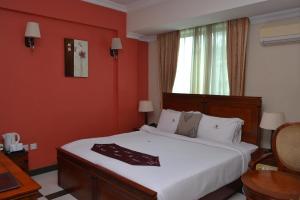 达累斯萨拉姆日航大厦酒店的卧室配有一张白色大床和红色的墙壁