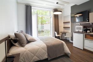 巴黎Les cles du 27 Paris的一间卧室配有一张床、一间厨房和一个窗口