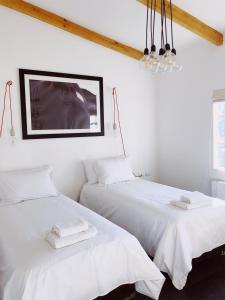 纳塔列斯港El Establo的白色客房内的两张床,配有白色床单