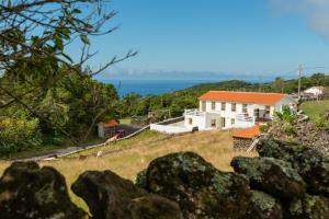 Calheta de NesquimCasa da Figueirinha的一座山丘上的房屋,背景是大海