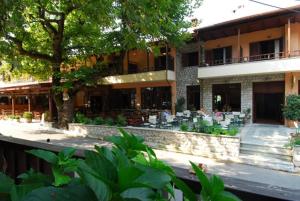 埃拉蒂特里卡隆Hotel Papanastasiou的前面设有桌椅的建筑