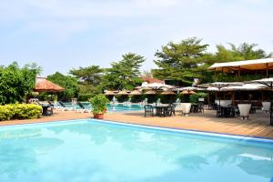布琼布拉Hotel Club du Lac Tanganyika的一个带桌椅和遮阳伞的游泳池