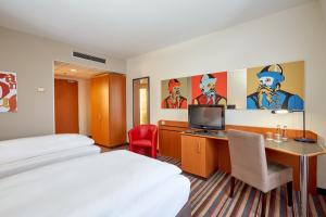 莱比锡H+莱比锡酒店的酒店客房设有一张床、一张书桌和一台电视机。
