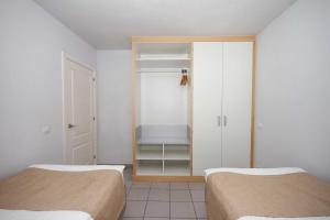 波多黎各特拉扎玛阳光套房塞瓦图尔酒店的一间设有两张床和一个带架子的衣柜的房间