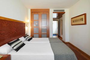 萨拉戈萨爱科赛德利西亚广场酒店的卧室配有一张白色大床和木制床头板