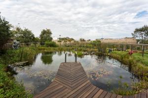 MatroosfonteinHotel Verde Cape Town Airport的花园中带木板路的池塘