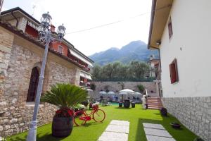 布雷佐内加尔达艾斯特之家住宿酒店的一座绿色的院子,在建筑里用红色的自行车