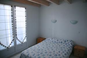 Grand-Village-PlageHotel Residence Les Alizes的一间卧室设有一张床和两个大窗户