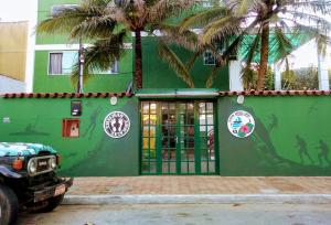 阿拉亚尔-杜卡布Pousada Arraial Caribe的一座绿色建筑,前面有棕榈树